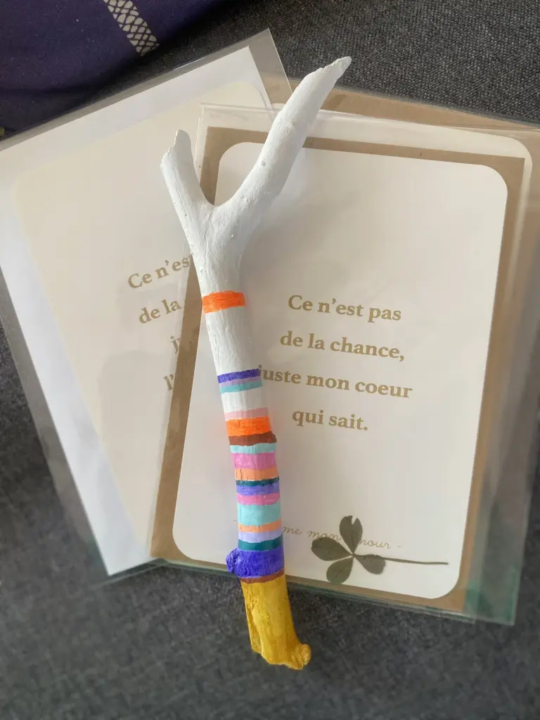 Baton de parole multico sur canapé gris avec des cartes Mantras et trèfle à 4 feuilles